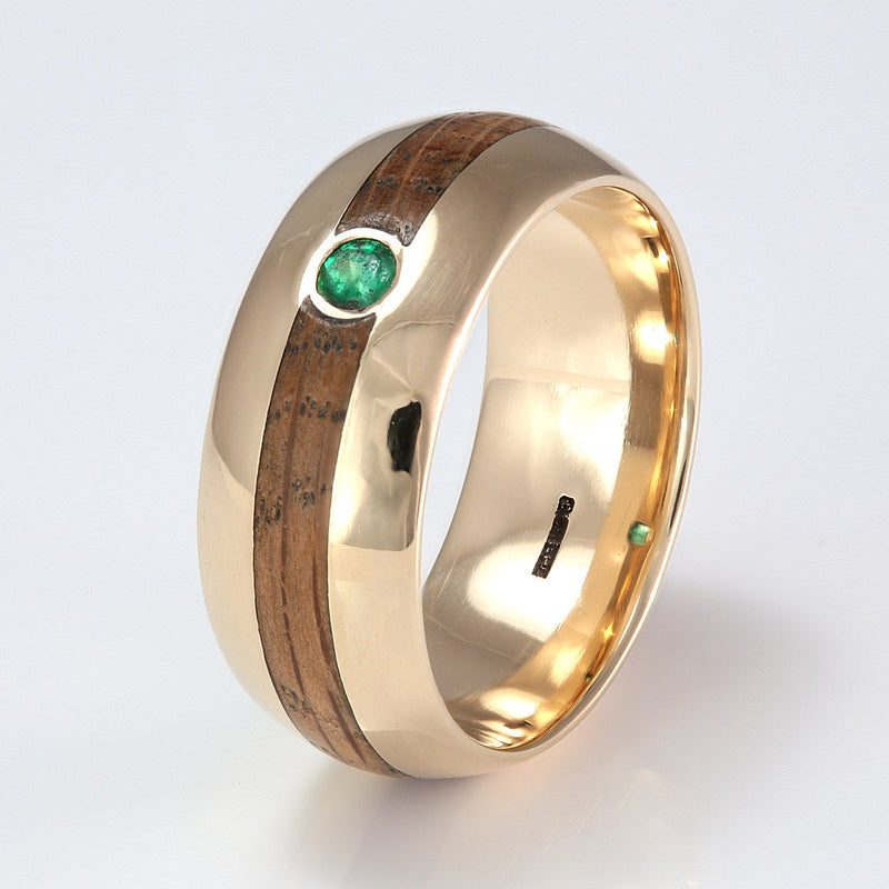 9mm wide rounded edge 9ct yellow gold ring with a centred inlay of oak meeting at a round emerald | by Eco Wood Rings UK