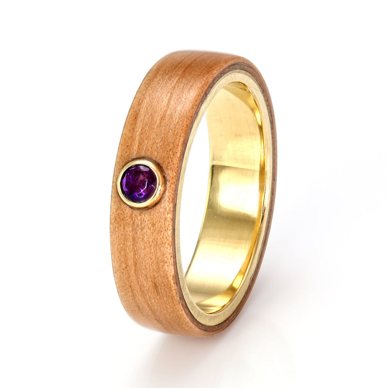 Apple wood ring with a polished yellow gold liner and a round amethyst in a yellow gold bezel setting | by Eco Wood Rings UK