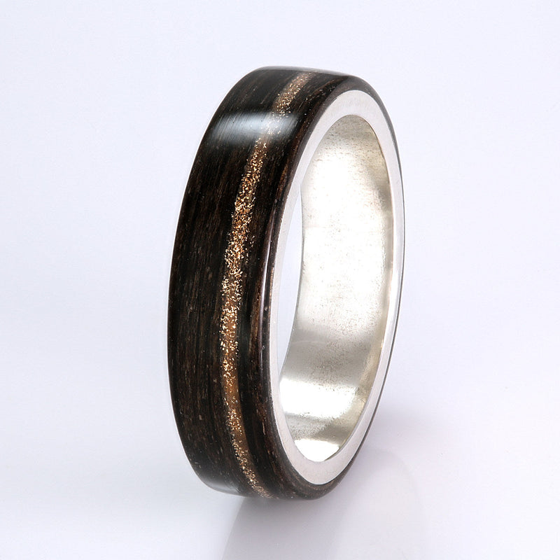 Custom wedding ring in bogwood with a silver liner and an off-centre inlay of hair and gold shavings