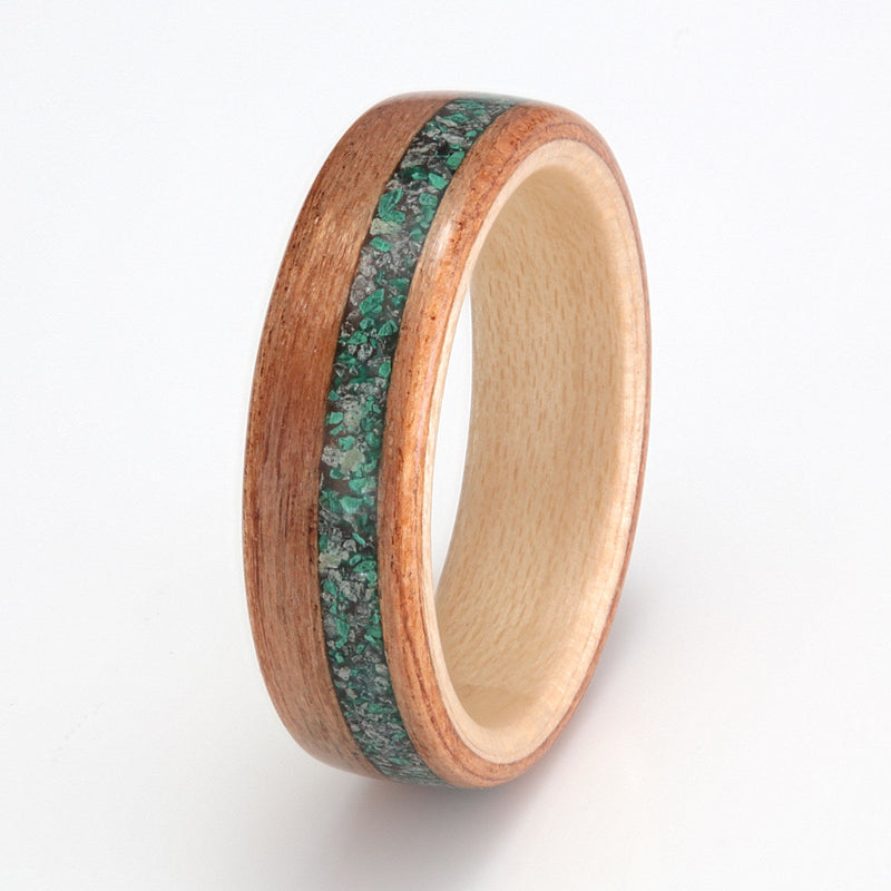 Ethical wedding ring made from cherry wood with a maple liner and an off centre inlay of emerald, tourmaline and malachite