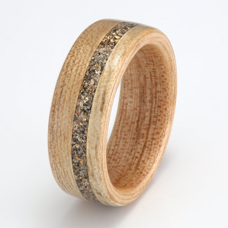 Custom wedding ring from materials with meaning | Elm bentwood ring with an off centre inlay of sand, granite & gold shavings